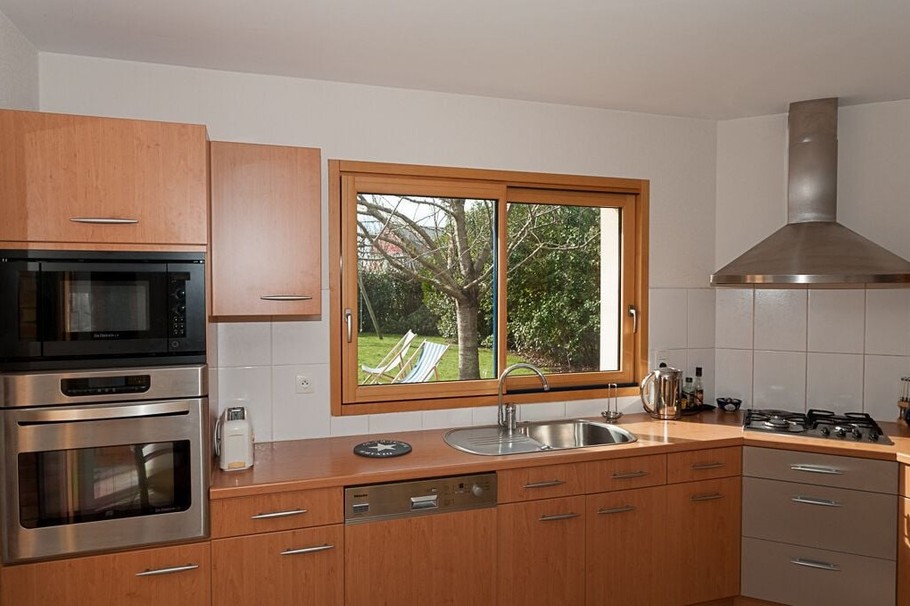 Cuisine toute équipée, avec vue sur le jardin arboré.