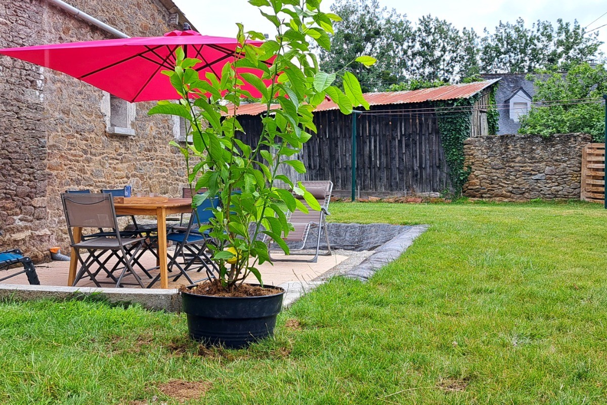 Terrasse ombragée et terrain clos avec pelouse et jeux pour enfants.