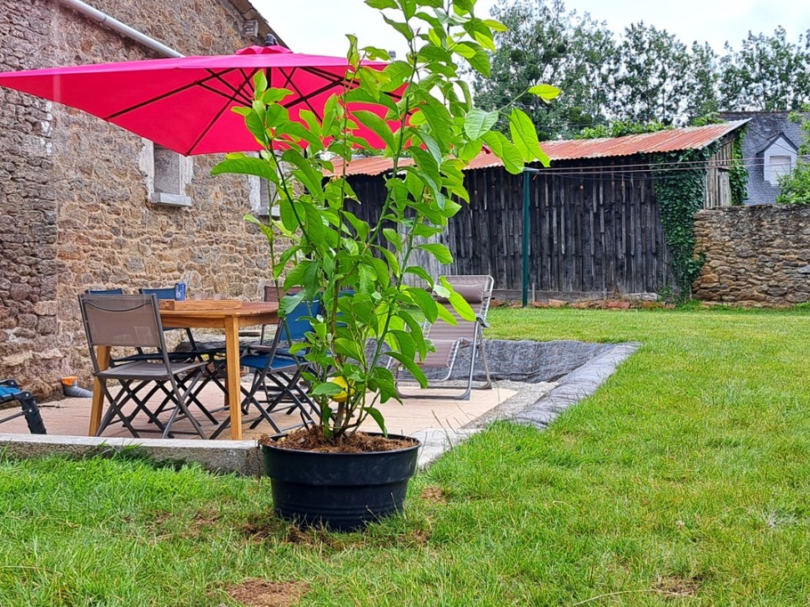 Terrasse ombragée et terrain clos avec pelouse et jeux pour enfants.