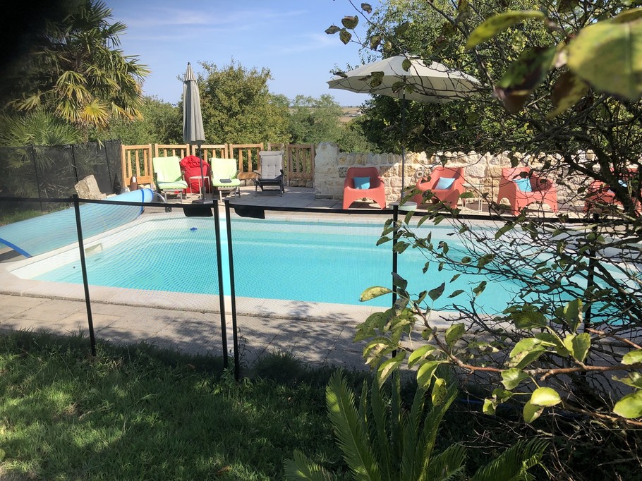 De nombreux sièges et parasols entourent la piscine.