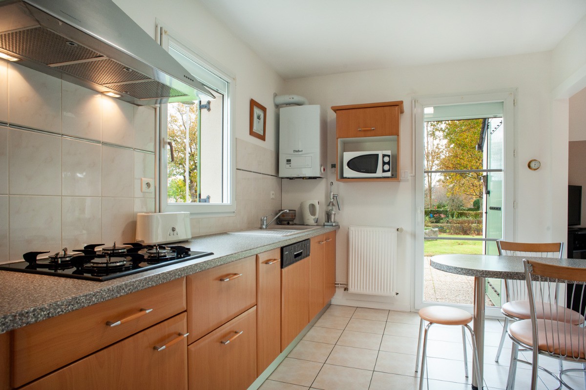 cuisine sortie sur jardin et sa table extérieure sous store banne