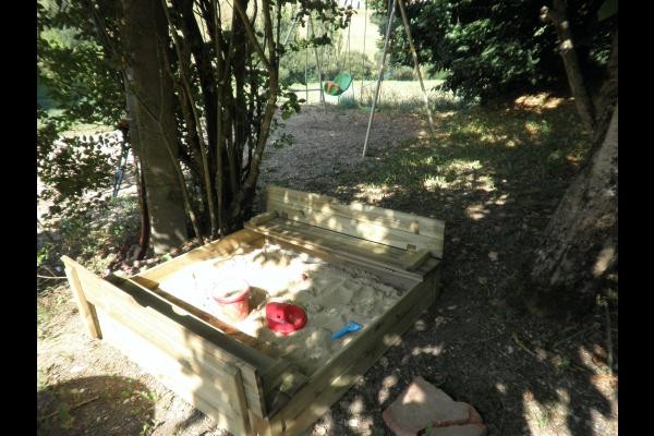 Le bac à sable en bois avec petits bancs intégrés