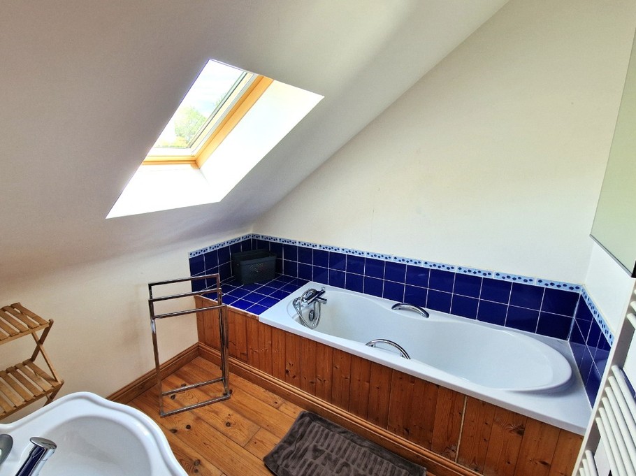 La salle de bain au 2nd étage, avec baignoire grande dimension. Parquet au sol.