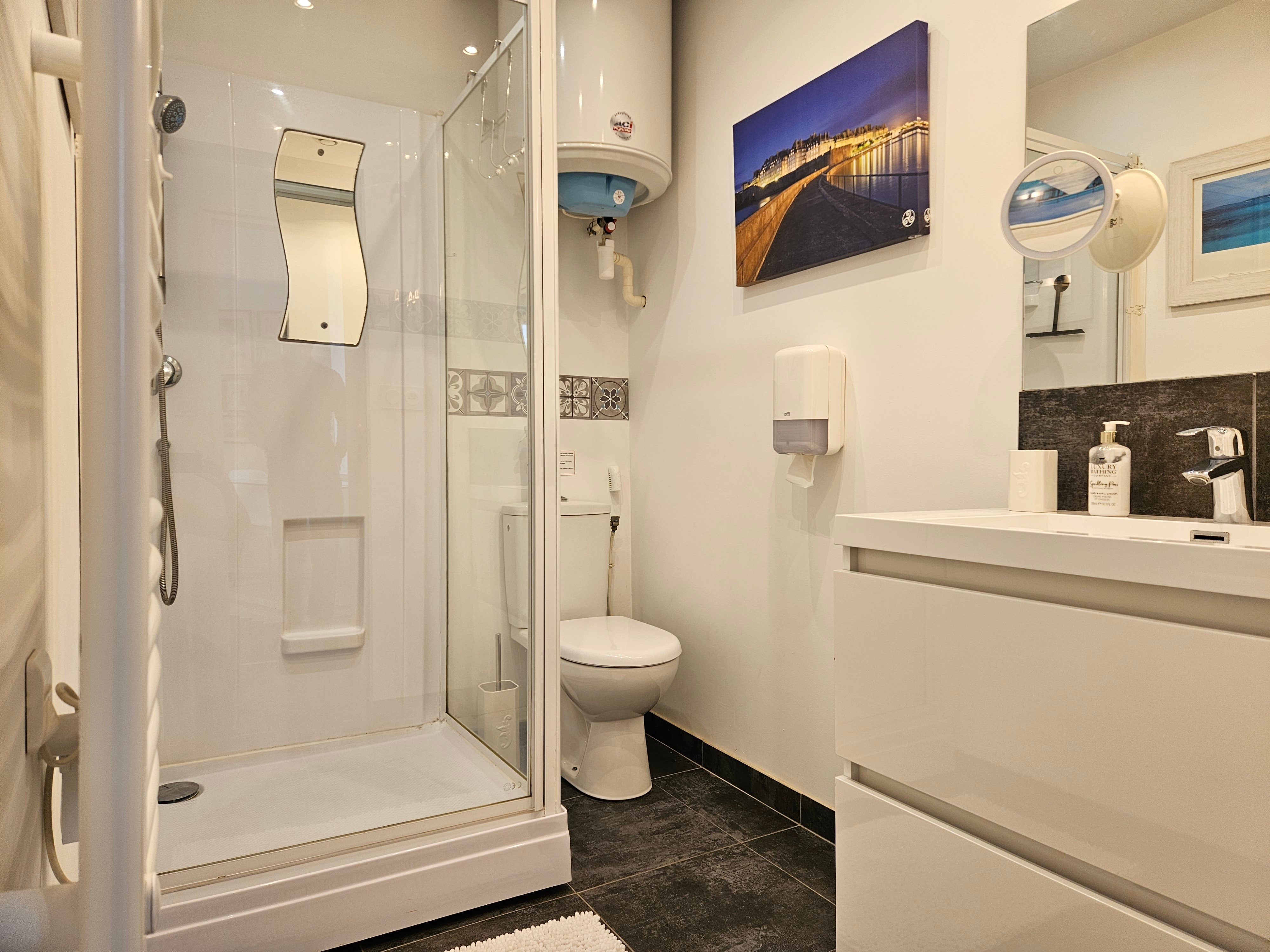 Salle d'eau avec meuble vasque, radiateur sèche serviette, douche grande dimension et WC, attenants à la chambre
