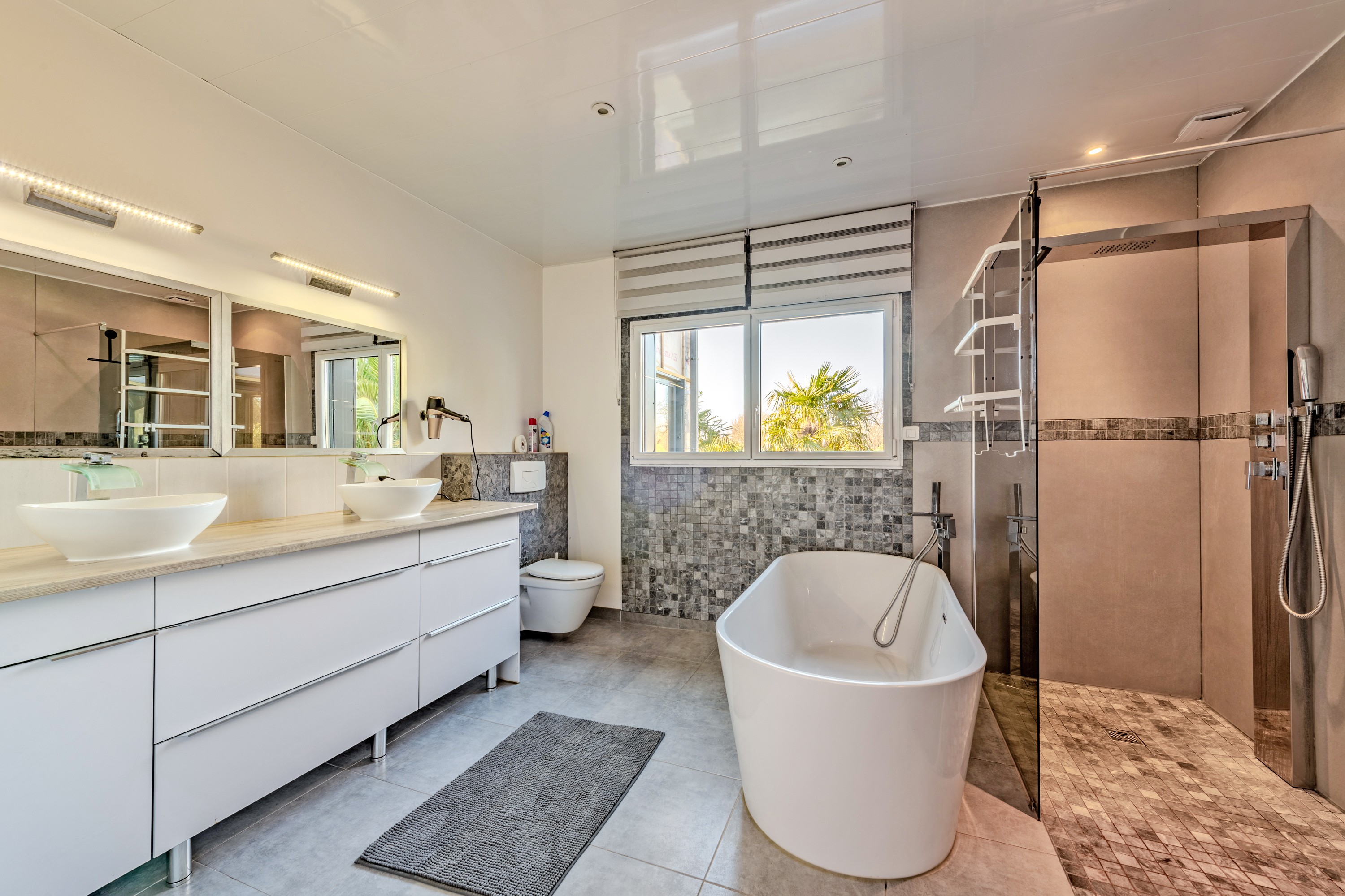 Salle de bain avec triple vasque, baignoire et douche.