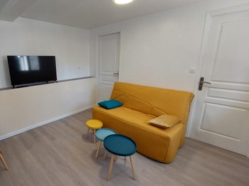 Salon avec canapé et télévision dans un gîte rénové