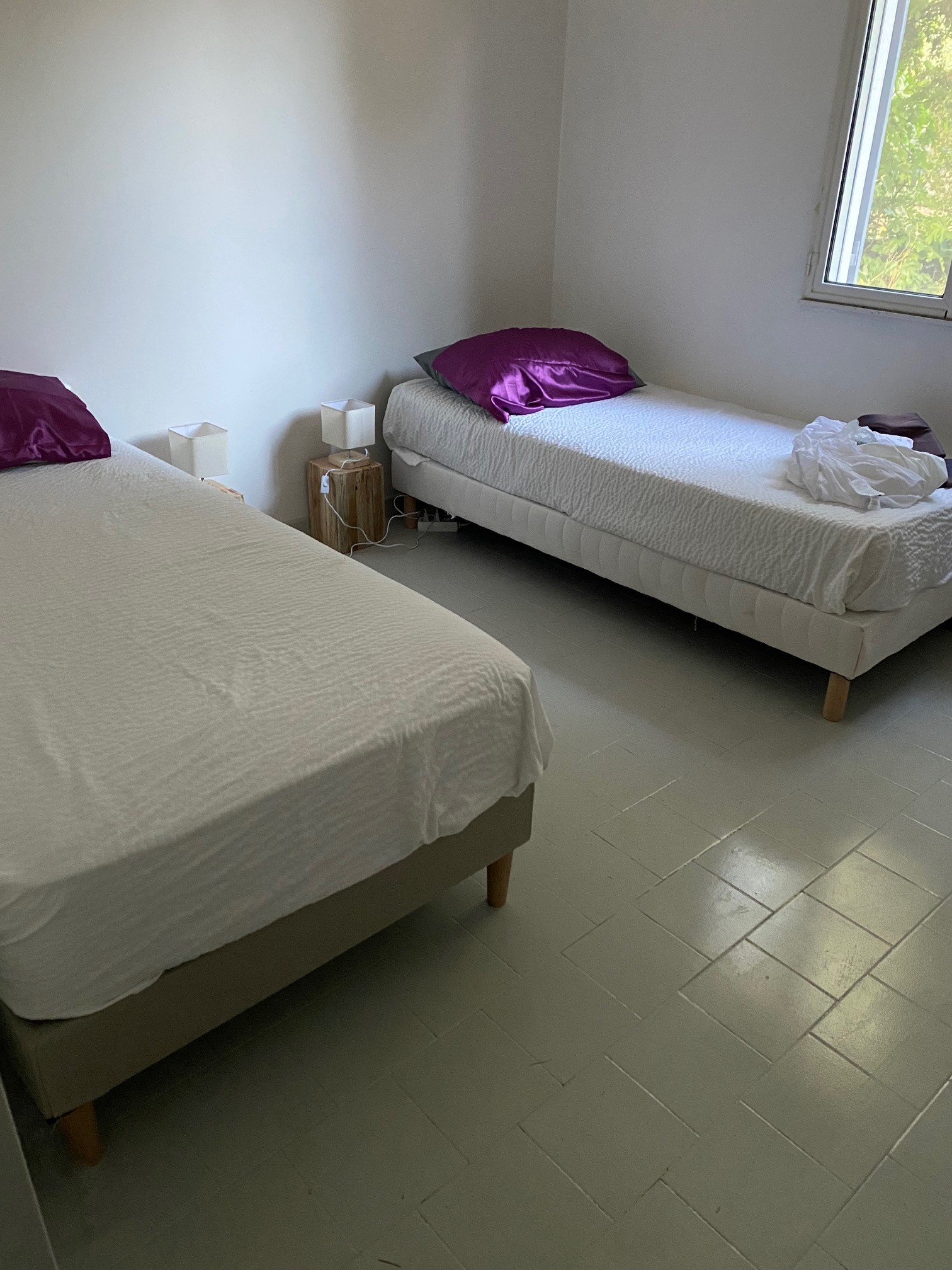 Sand-coloured bedroom, 2 single beds, ceiling fan, storage space.