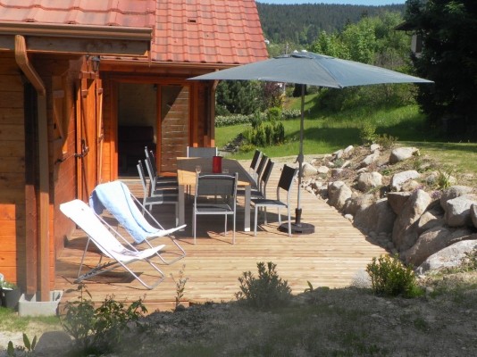 Grande terrasse en bois avec salon de jardin. Ouverture sur séjour.