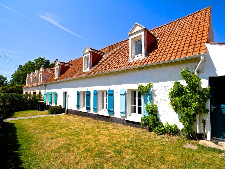 Façade de la maison et jardin ensoleillé.