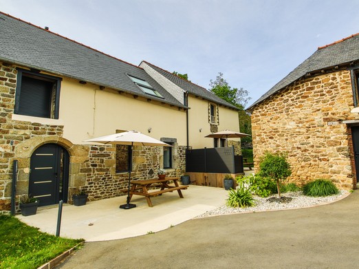 Façade du gîte avec sa terrasse. Autre gîte mitoyen à droite