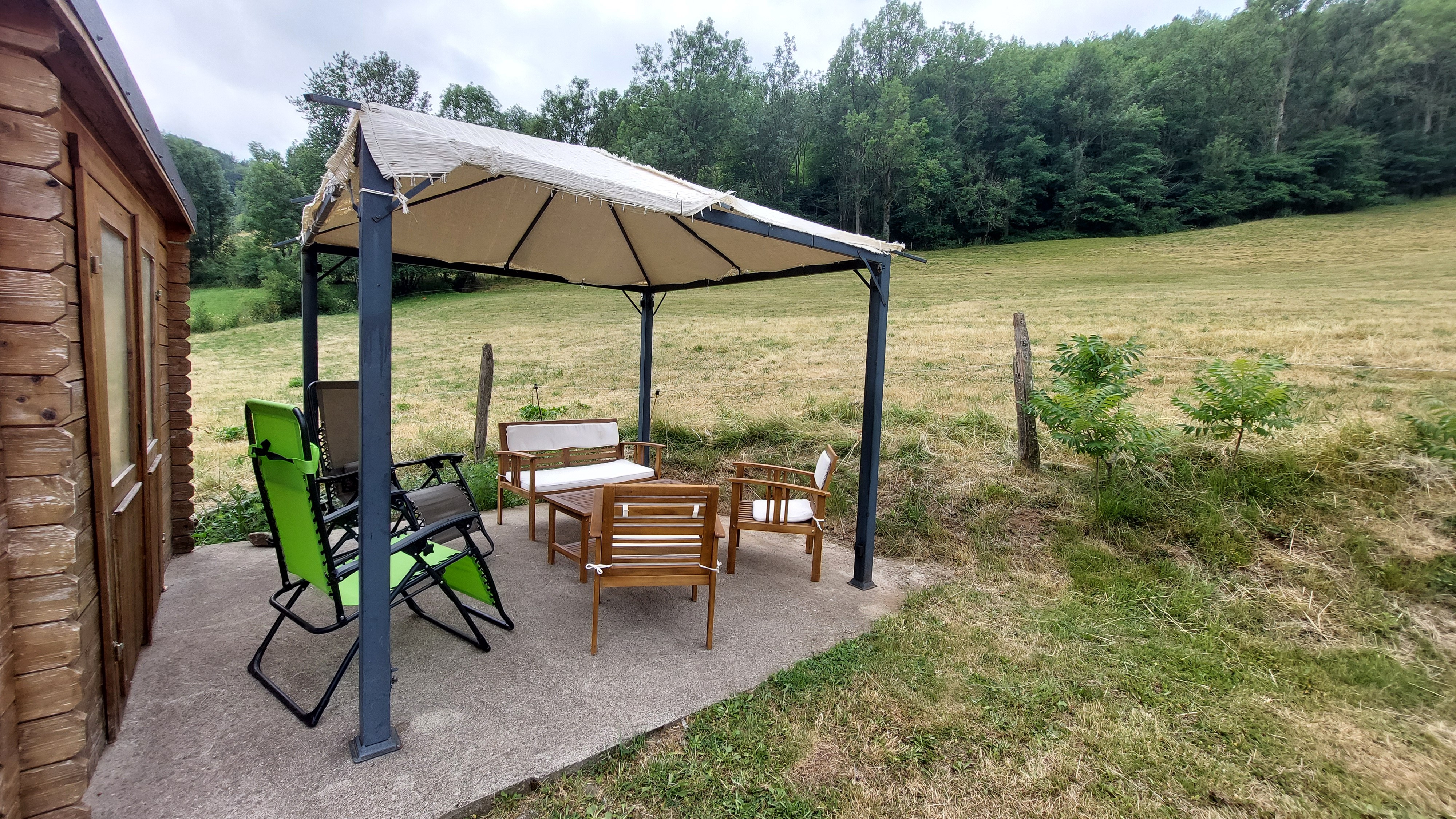 Salon de jardin sous tonnelle avec vue sur la montagne – Gîte à Laveissière dans le Cantal