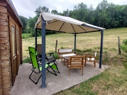 Salon de jardin sous tonnelle avec vue sur la montagne – Gîte à Laveissière dans le Cantal