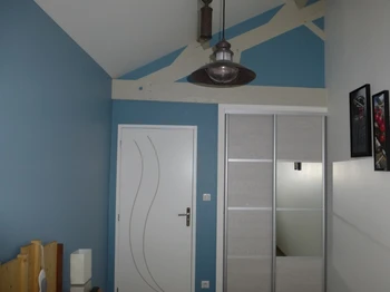 Chambre bleue avec deux lits simples, placard et TV.