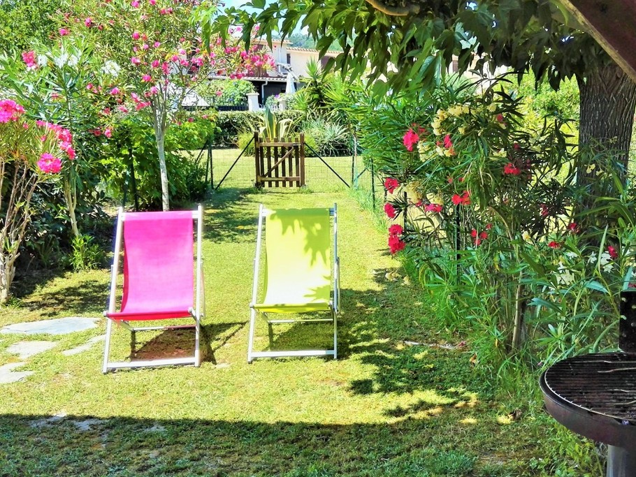 Le jardin devant la terrasse couverte, avec transats et barbecue pour farniente et grillades.