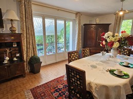 Le séjour pour y prendre son petit-déjeuner et salon à droite avec un canapé, pouf, bibliothèque une cheminée et table basse