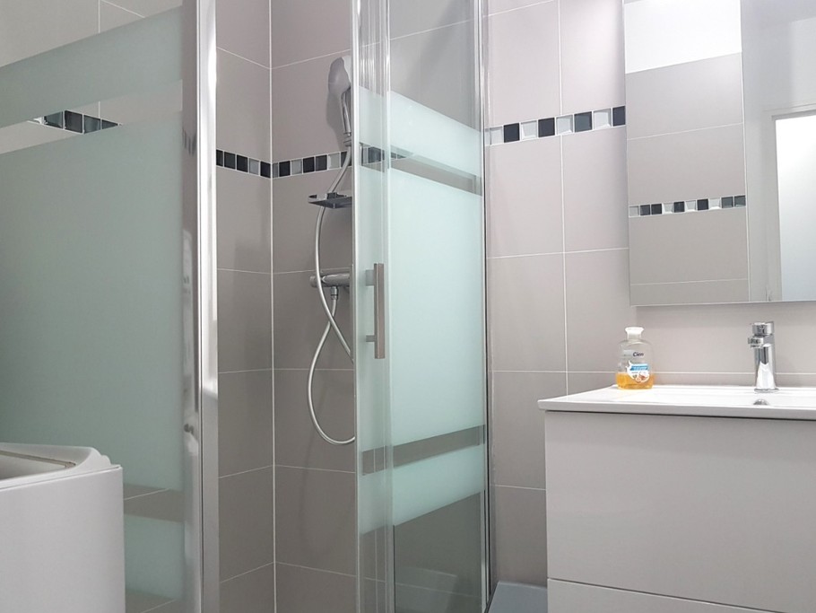 Salle d'eau avec une douche grande dimension, lavabo meuble vasque, machine à laver, sèche serviette électrique. WC séparé.