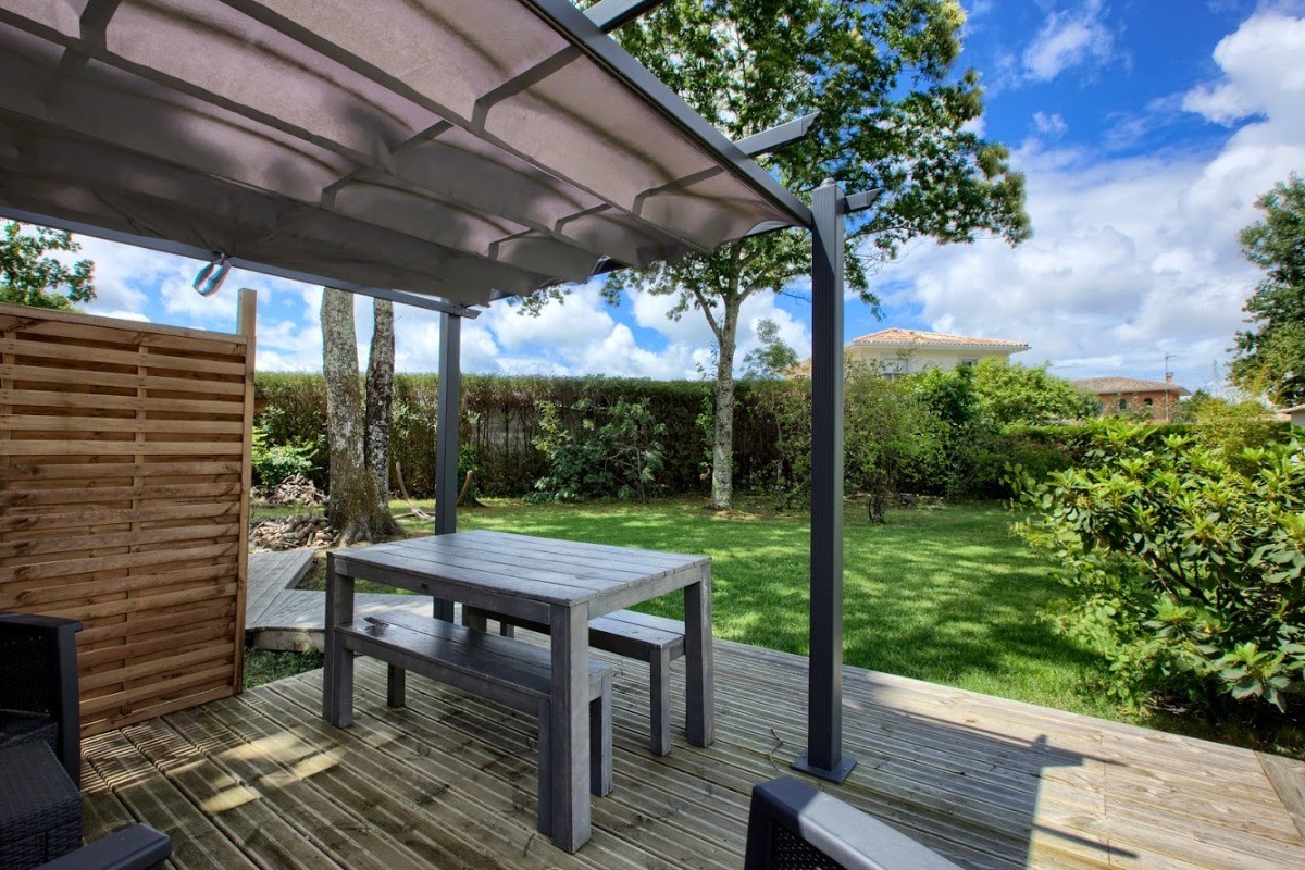 Salon et table de jardin sous la tonnelle.