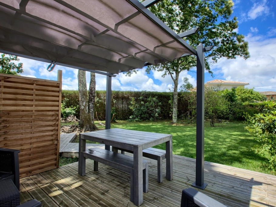 Salon et table de jardin sous la tonnelle.