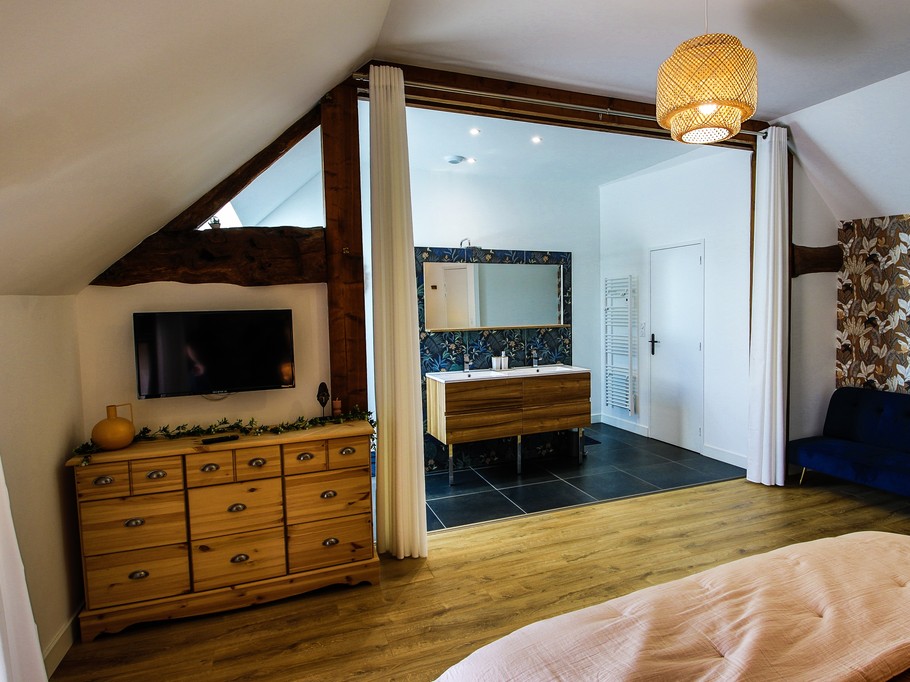 Chambre 1 : chambre spacieuse pour deux personnes avec lit 160x200 cm, TV, canapé, et sa grande salle de bain double vasques (baignoire et douche) et WC séparés.