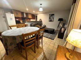 Pièce de vie au RDC avec coin cuisine, coin salon avec TV et coin séjour avec table à manger.