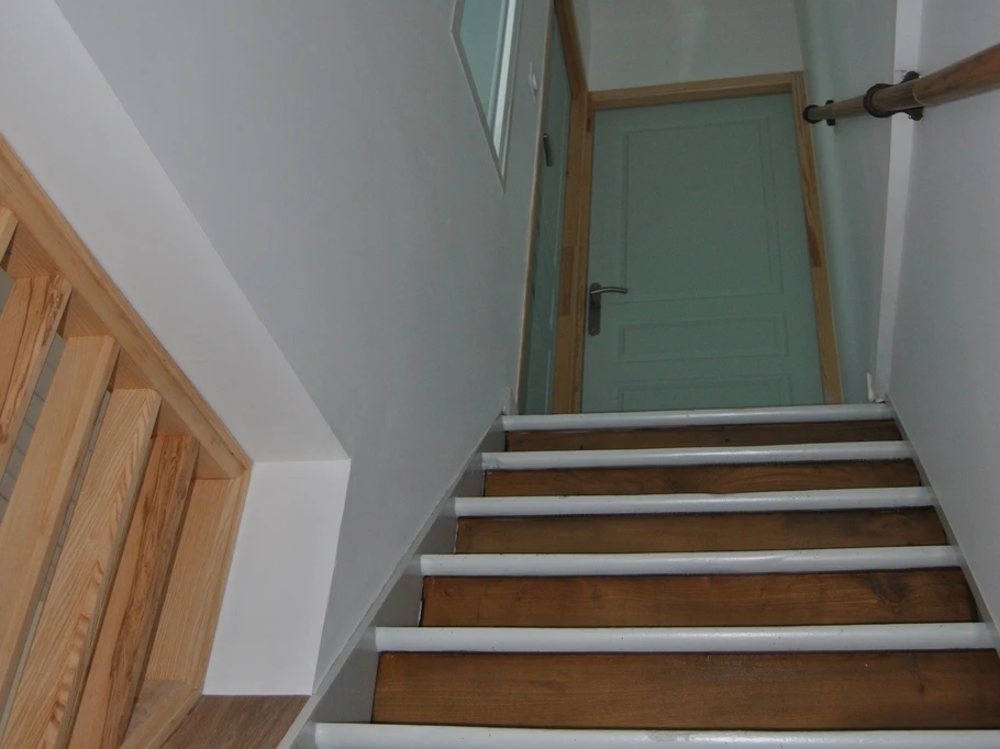 couloir d'accès aux chambres avec son escalier et un détecteur de fumée sur le plafond du palier.