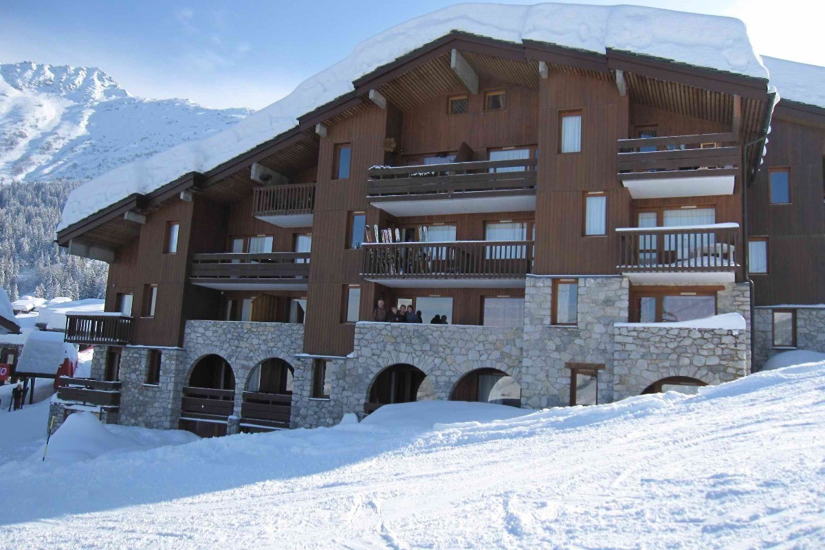 La façade du chalet depuis la piste : la famille au balcon