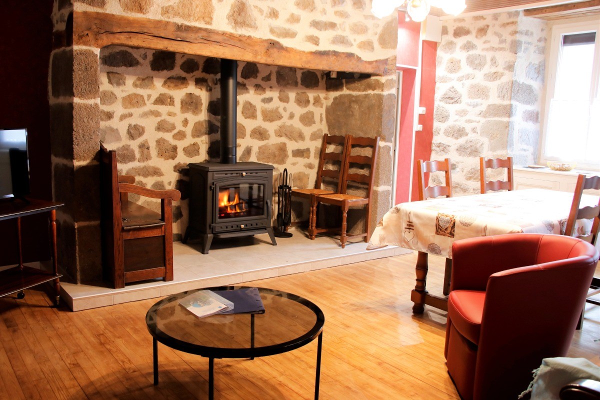 Salon chaleureux avec poêle à bois, canapé confortable et ambiance rustique dans le gîte
