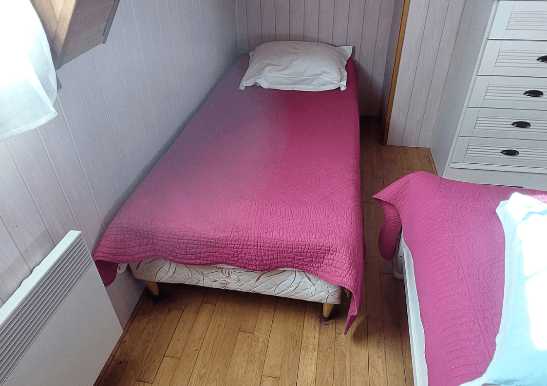 Vue sur la chambre du gîte avec lit simple et décoration rustique.
