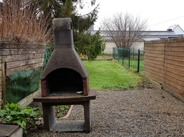 Terrasse abritée avec salon de jardin, barbecue fixe et jardin clôturé.