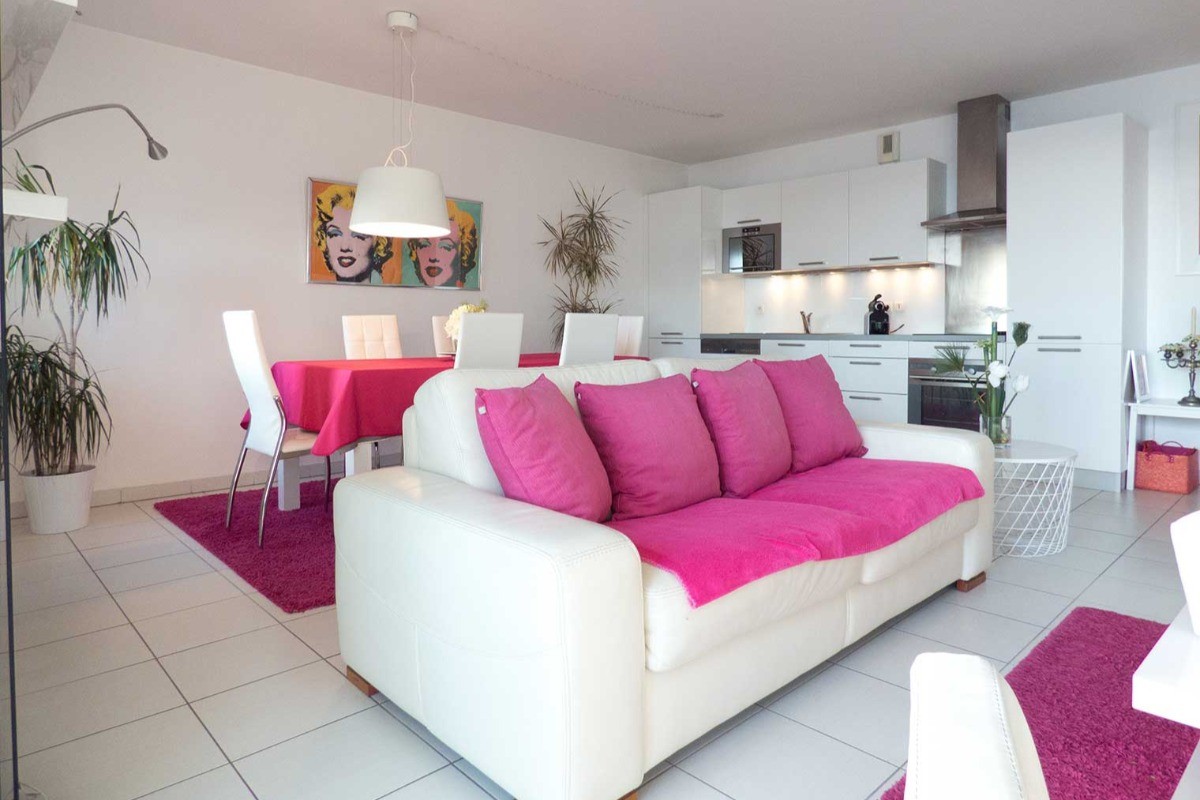 Very bright living room with sitting area, living area and kitchen area. View over the marina at the foot of the Saint-Malo ramparts.