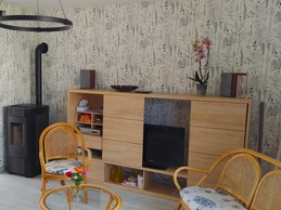 Pièce de vie au RDC avec entrée, cuisine, séjour, salon et poêle à bois.