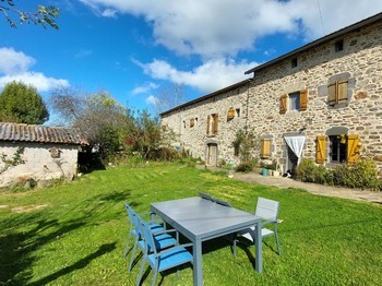Jardin verdoyant de la maison d'hôtes avec espace détente, idéal pour une pause nature dans le Cantal