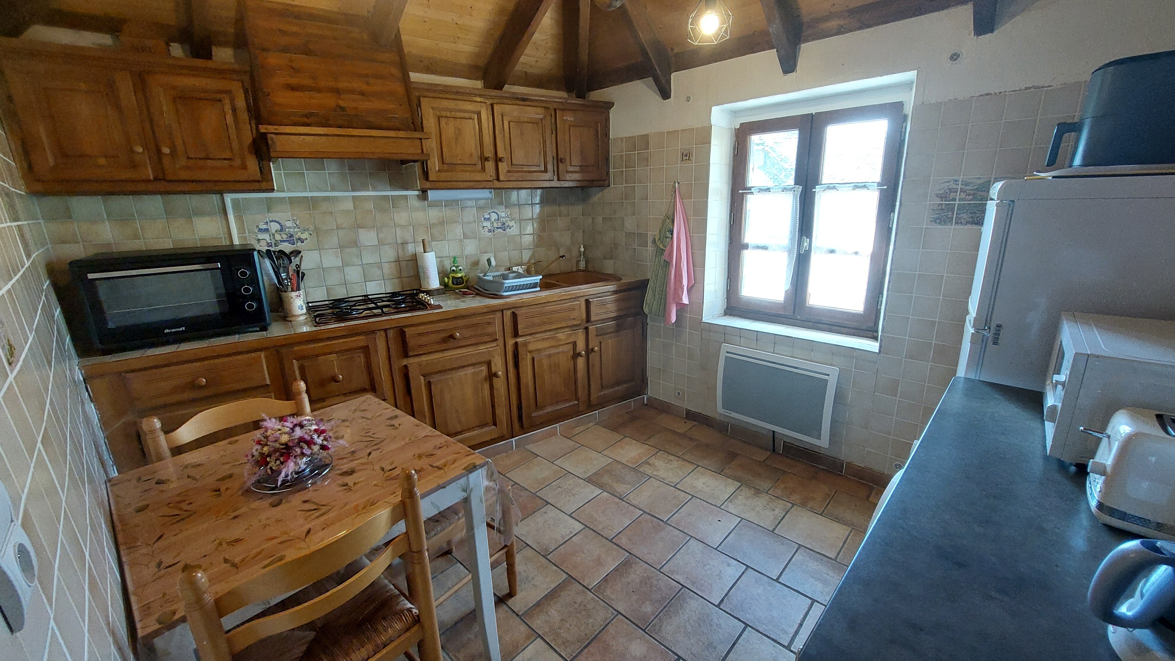 Fully equipped kitchen with wooden units in an authentic Cantal gîte
