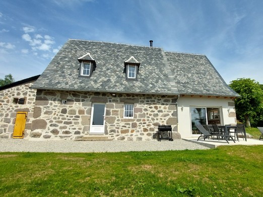 Façade en pierre du gîte La Petite Maison à Saint-Étienne-de-Carlat, Cantal, avec toit en ardoises.
