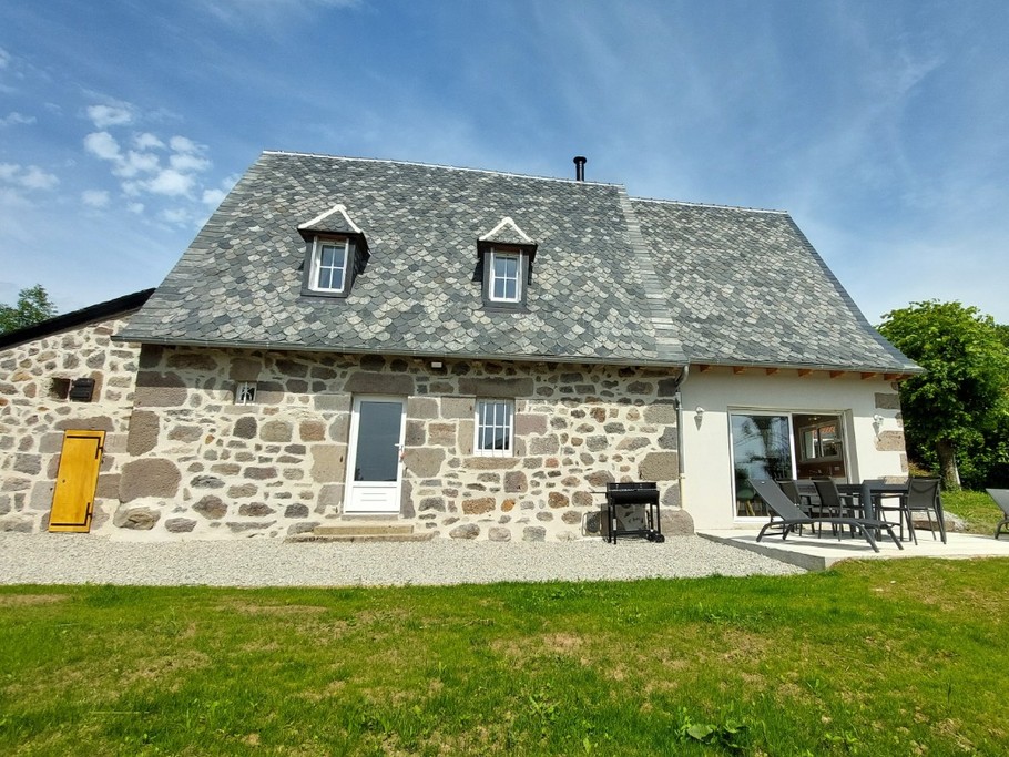 Façade en pierre du gîte La Petite Maison à Saint-Étienne-de-Carlat, Cantal, avec toit en ardoises.