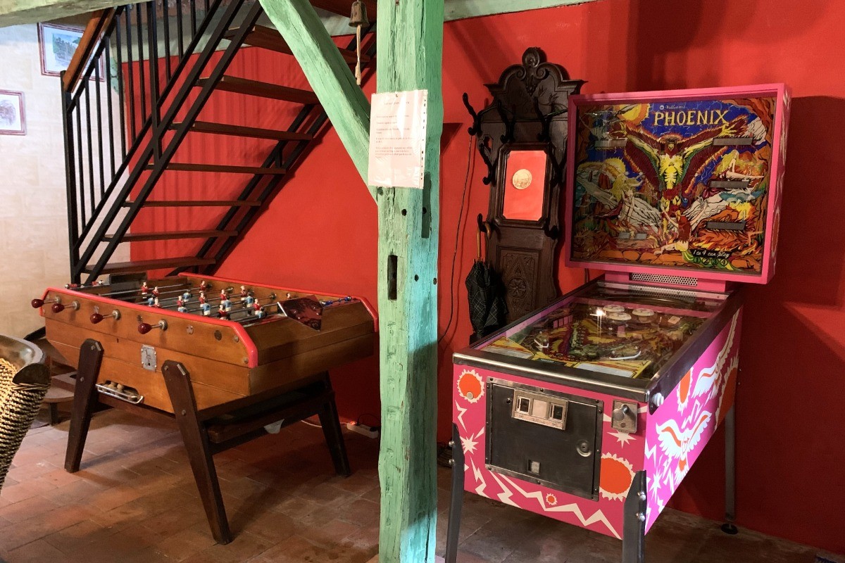 Second séjour avec jeux vintage (babyfoot, flipper, jeux d'arcade). Canapé-lit convertible pour 2 personnes (140x190 cm). Dessert la cuisine à gauche, le salon à droite, les chambres à l'étage.