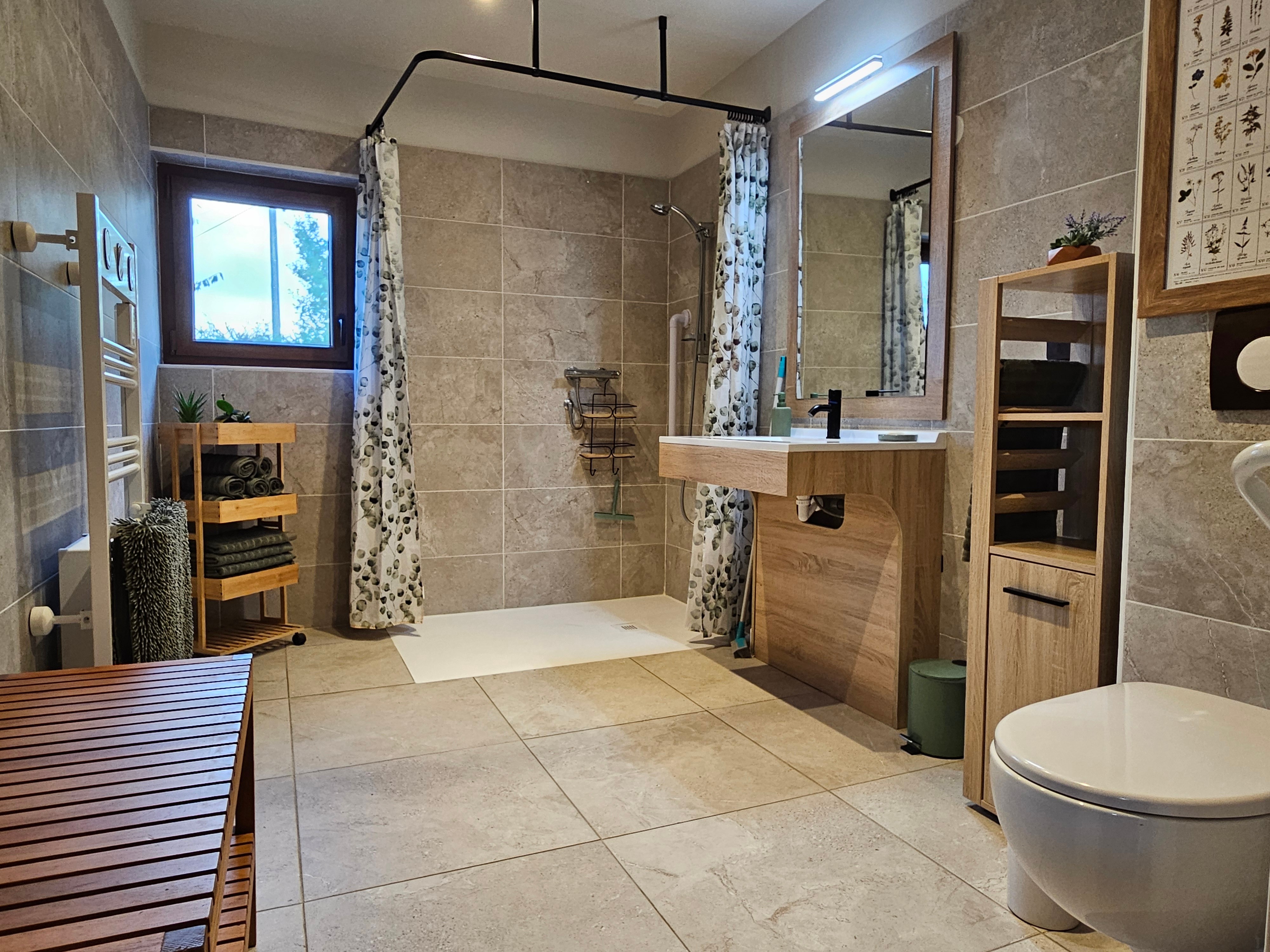 Accessible bathroom with a large shower, toilet and heated towel rail.