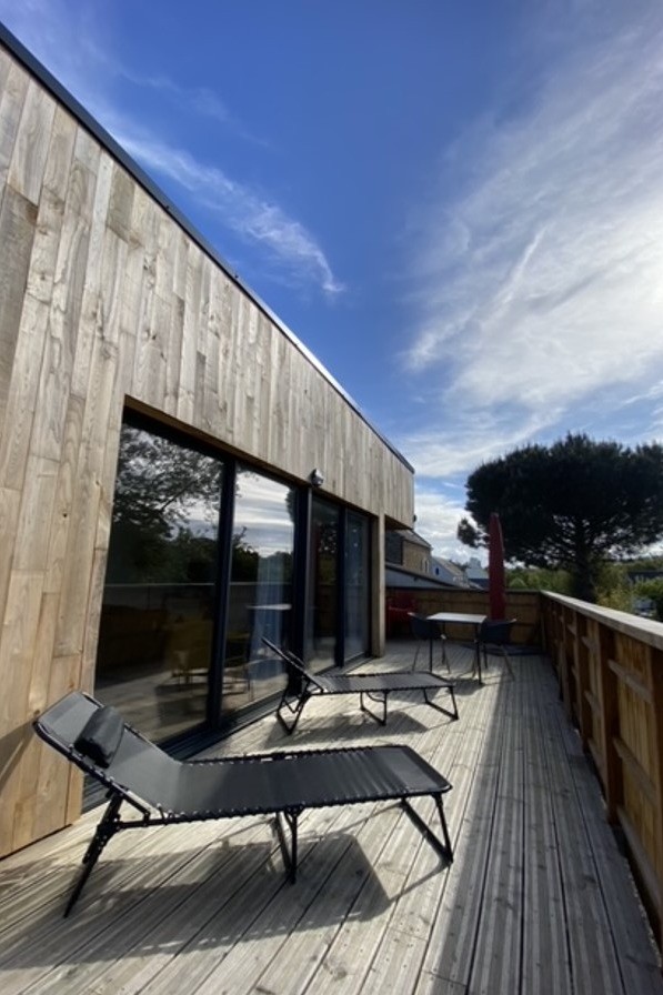 Grande terrasse de plus de 40 mètres carrés avec transats et salon de jardin.