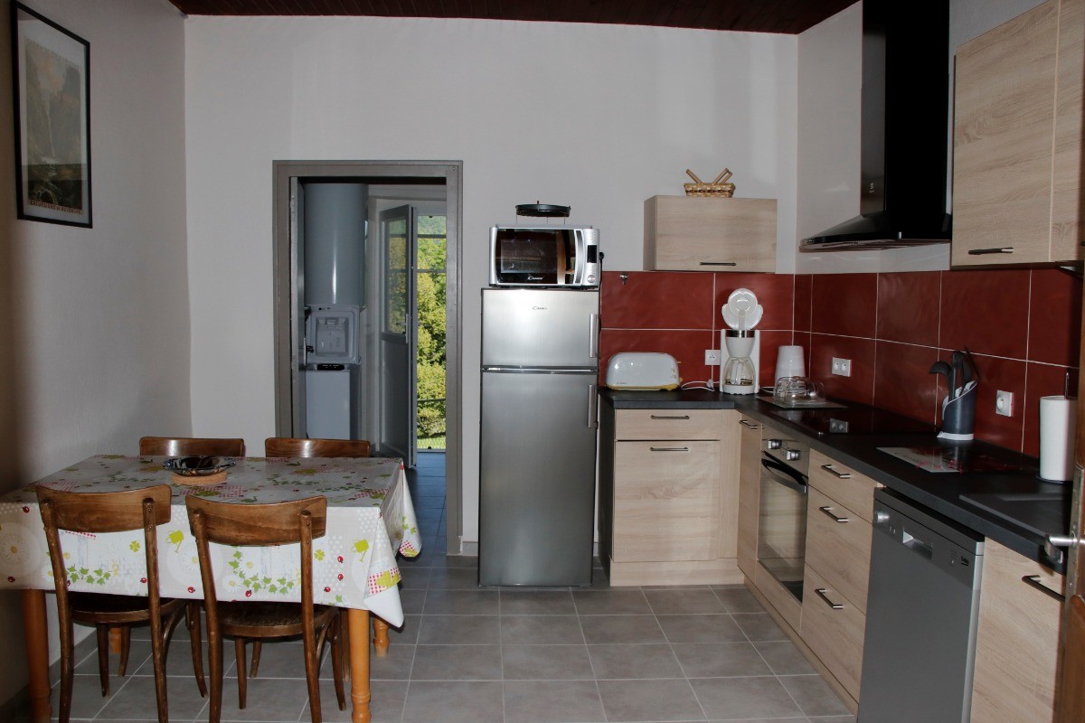 Cuisine équipée avec électroménagers modernes et table repas, idéale pour préparer de délicieux repas.