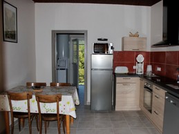 Cuisine équipée avec électroménagers modernes et table repas, idéale pour préparer de délicieux repas.