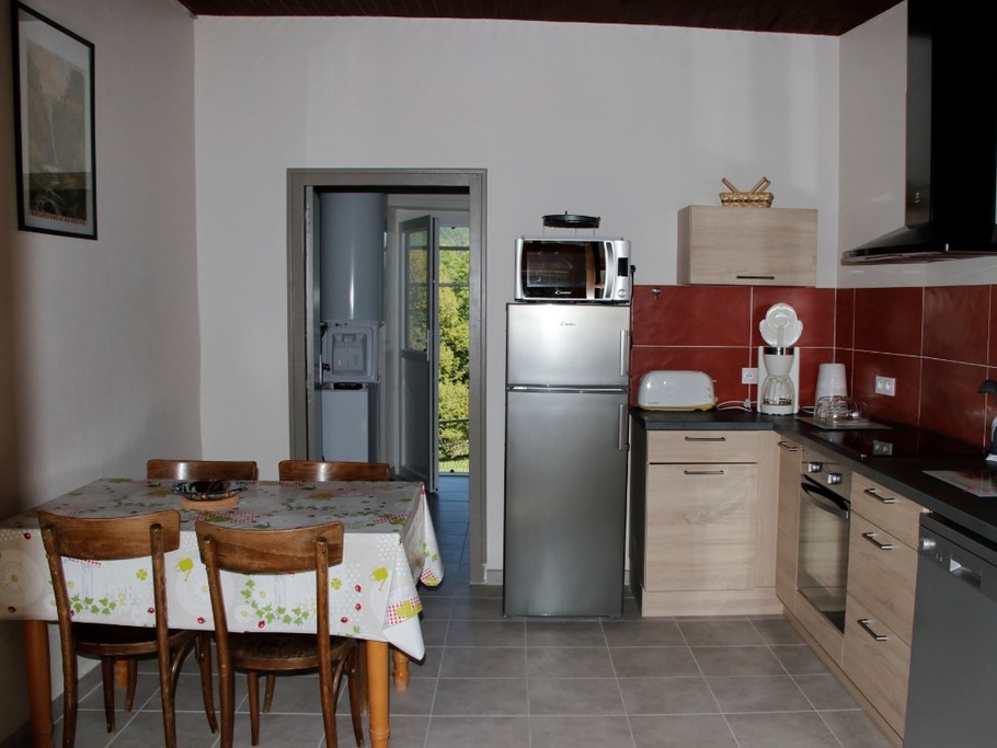 Cuisine équipée avec électroménagers modernes et table repas, idéale pour préparer de délicieux repas.