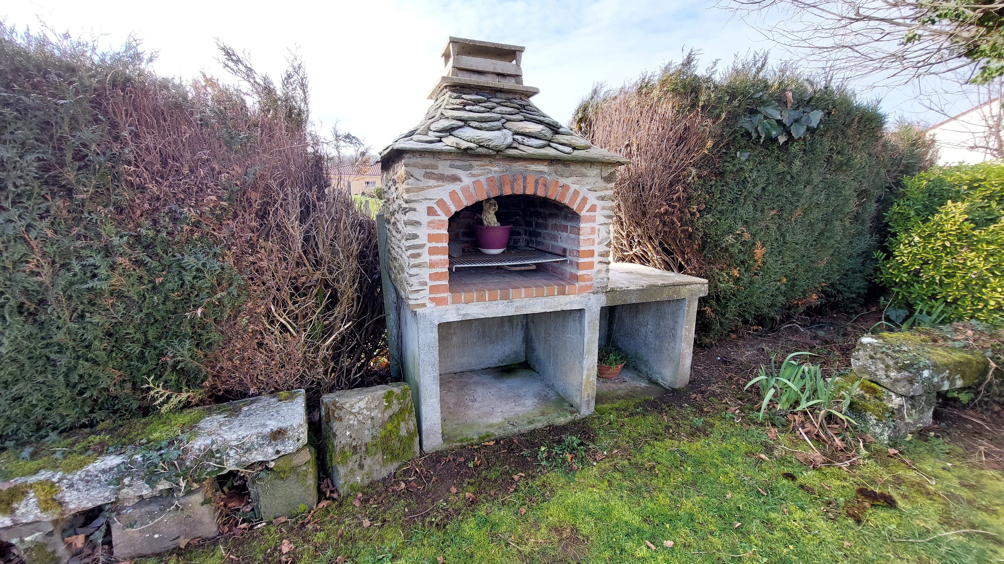 Barbecue en pierre dans le jardin du gîte