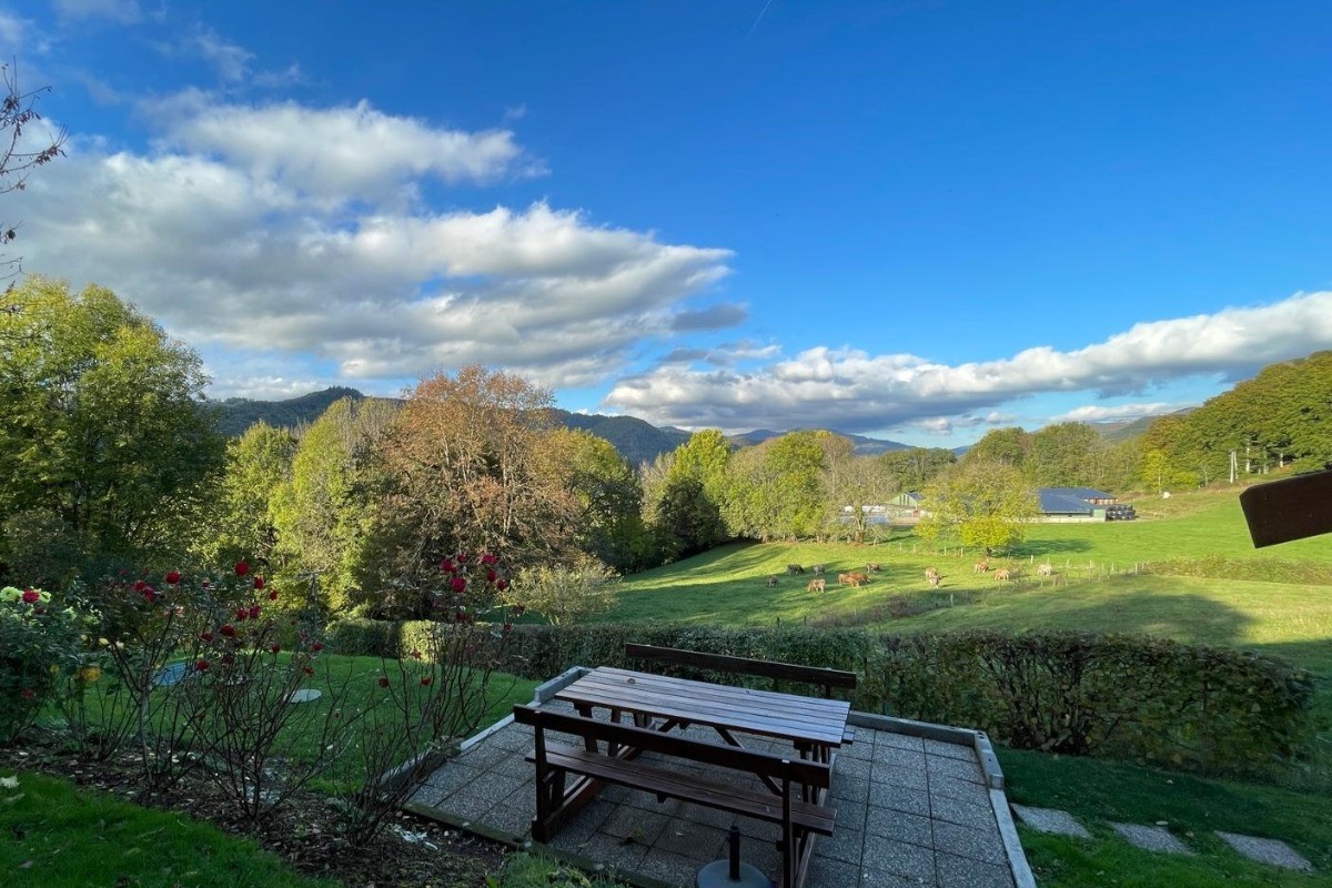 Deuxième terrasse aménagée dans le jardin avec table et bancs, idéale pour se détendre face aux montagnes