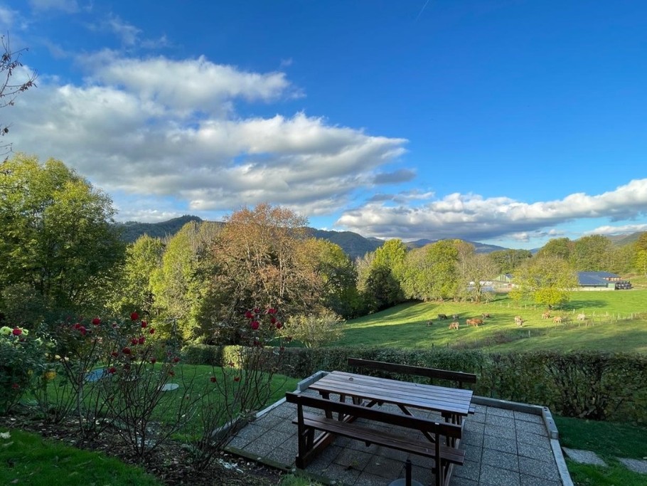 Deuxième terrasse aménagée dans le jardin avec table et bancs, idéale pour se détendre face aux montagnes