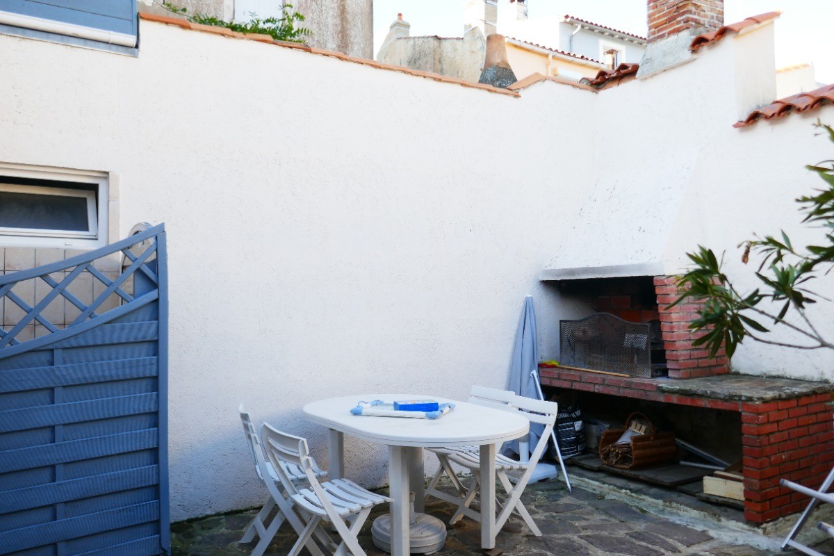 Cour avec salon de jardin, barbecue et douche extérieure donnant sur la salle de vie