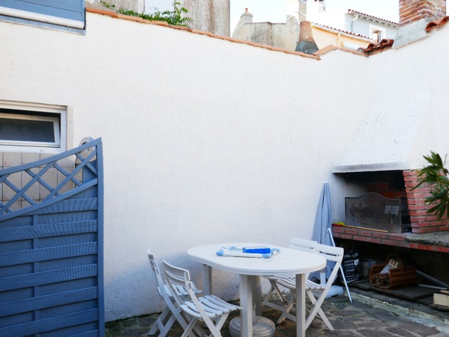 Cour avec salon de jardin, barbecue et douche extérieure donnant sur la salle de vie