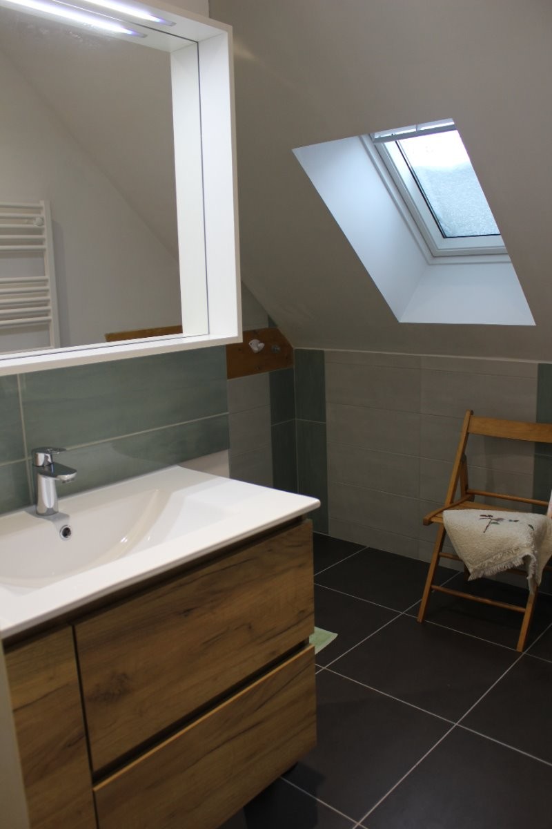 La salle de bain avec vasque, miroir et volumes de rangement