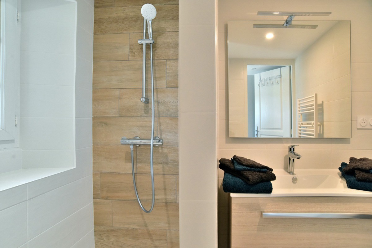 Salle d'eau avec douche à l'italienne spacieuse, meuble vasque et radiateur sèche serviette.