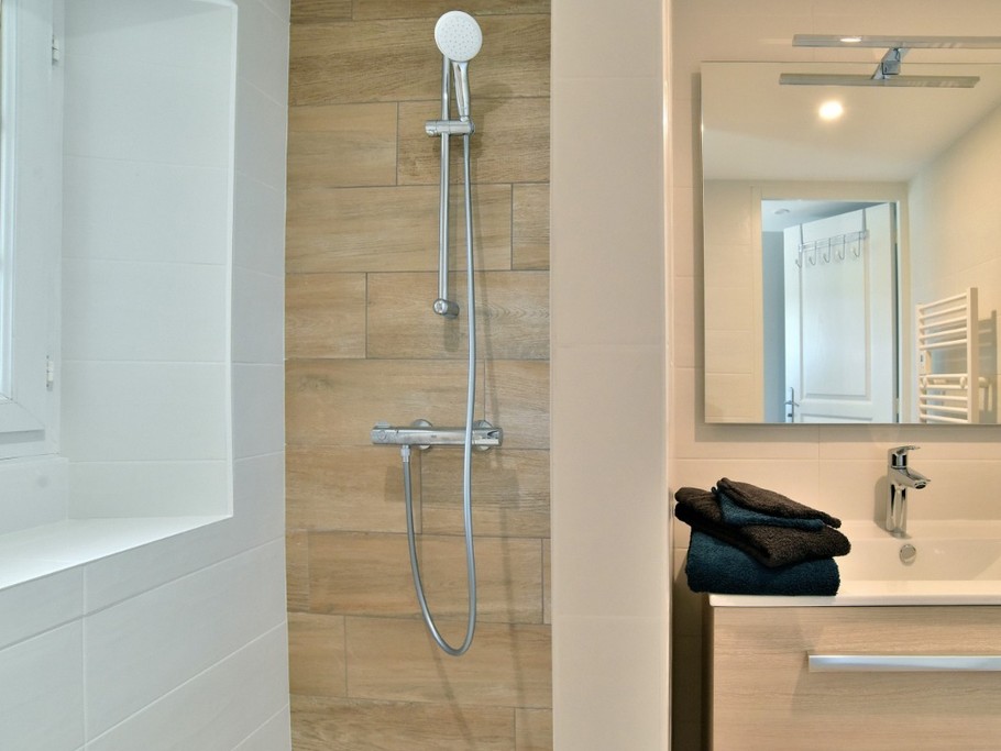 Salle d'eau avec douche à l'italienne spacieuse, meuble vasque et radiateur sèche serviette.