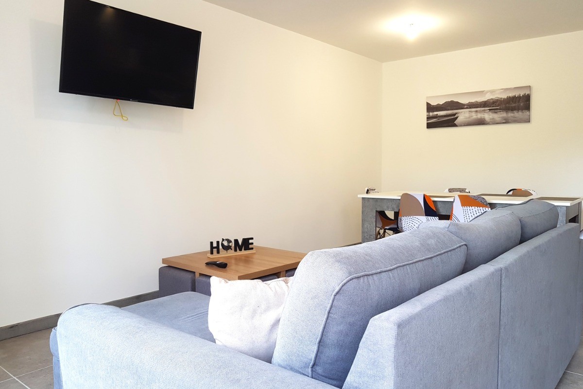 Grande pièce de vie de 32 m² avec coin cuisine toute équipée, coin séjour et coin salon. Accès à la terrasse de plain-pied.